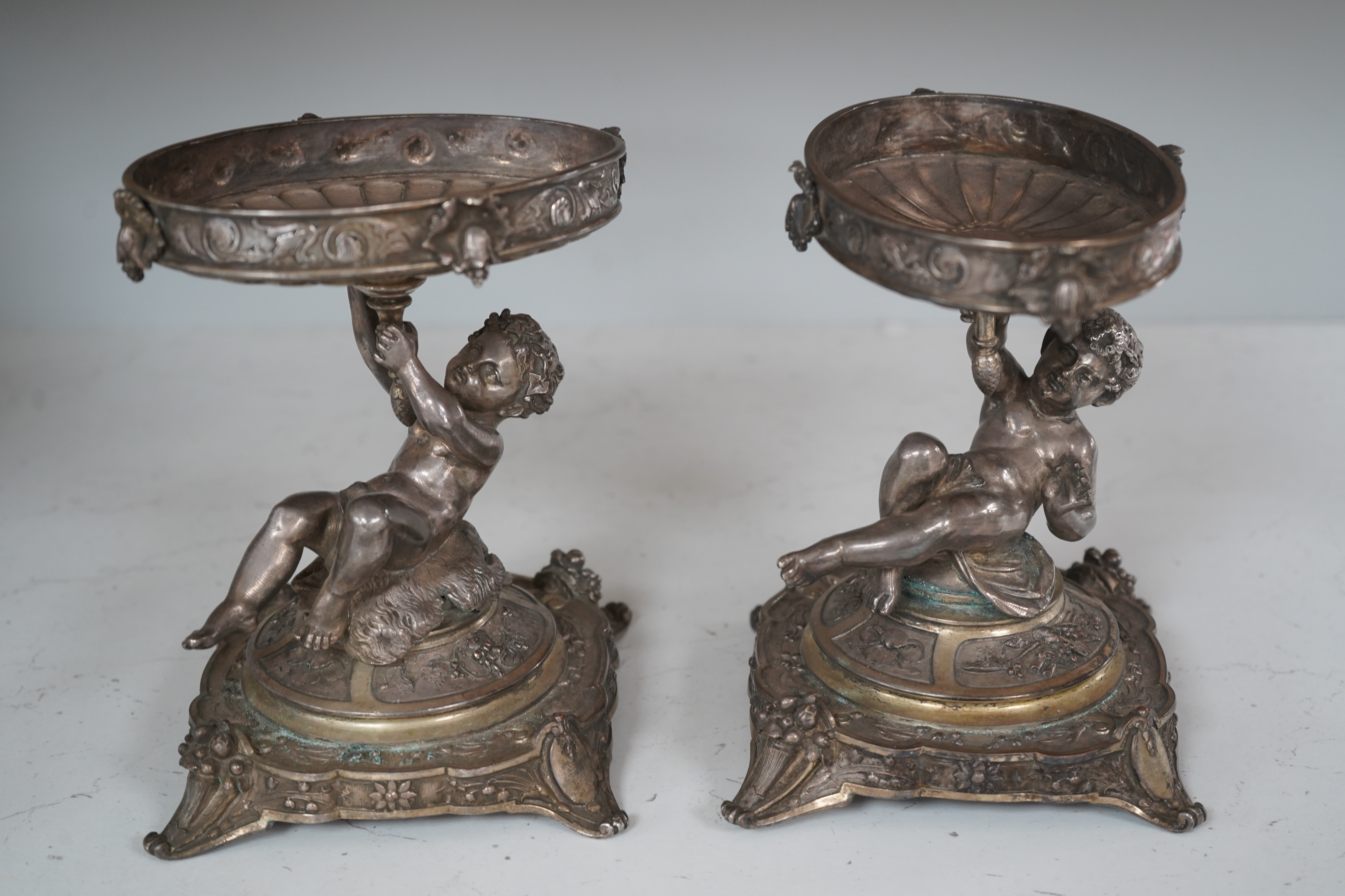 A pair of early 20th century Elkington & Co. silver plated ‘putti’ stands, 17cm. Condition - fair to good